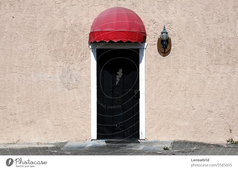 Metalltür mit kleinem roten Dach an einem sonnigen Tag Hintergrund Gebäude Großstadt Textfreiraum Tür Eingang Fassade Haus im Freien außerhalb Wand zugeklappt