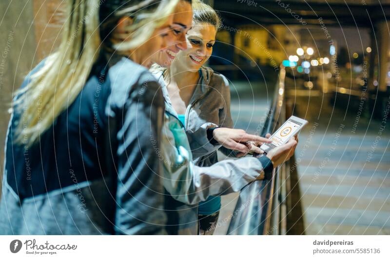 Lächelnd Frauen Läufer Freunde Überprüfung ihrer Aktivität Zusammenfassung auf Tracker Handy-Anwendung Glück Mobile Telefon klug Smartphone App Sport Team
