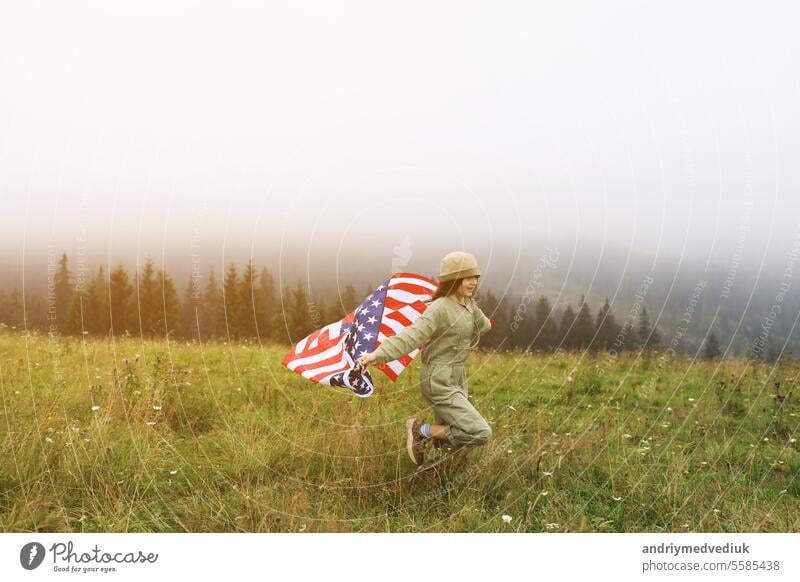 Schönes Kind Mädchen in Hut mit der amerikanischen Flagge auf nebligen Bergen. Independence Day der Vereinigten Staaten USA am 4. Juli mit Familie. Freiheit. Amerikanische patriotischen Urlaub Konzept