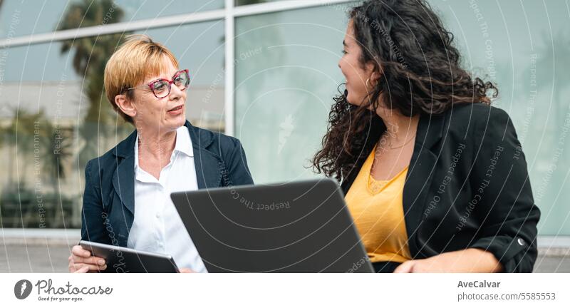 Geschäftsfrauenpaar vor einem Bürogebäude, das während eines Brainstormings Ideen austauscht. im Freien Person Business Erwachsener Laptop Sitzung Teamwork