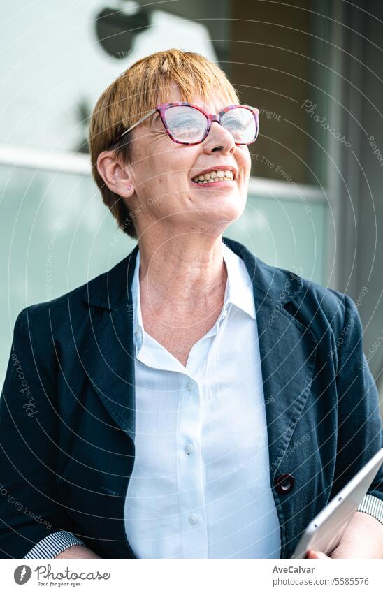 Ältere Geschäftsfrau vor einem Firmengebäude, glücklich in die Kamera lächelnd, Frau im Geschäft Büro Kollege Business Person Frauen Porträt Lifestyle Glück