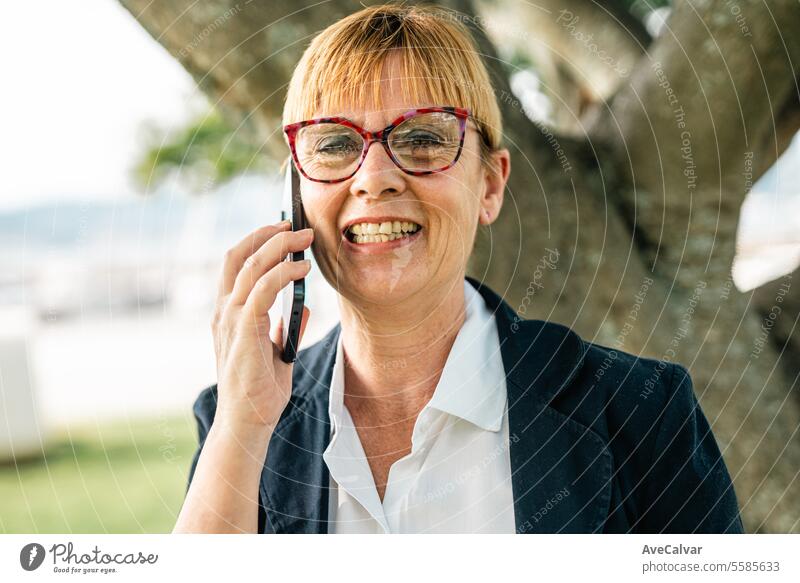 Ältere hispanische Frau, die im Freien ein Smartphone benutzt, um ein Geschäft abzuschließen Frau im Geschäft während der Bürozeiten Kollege Lifestyle Telefon