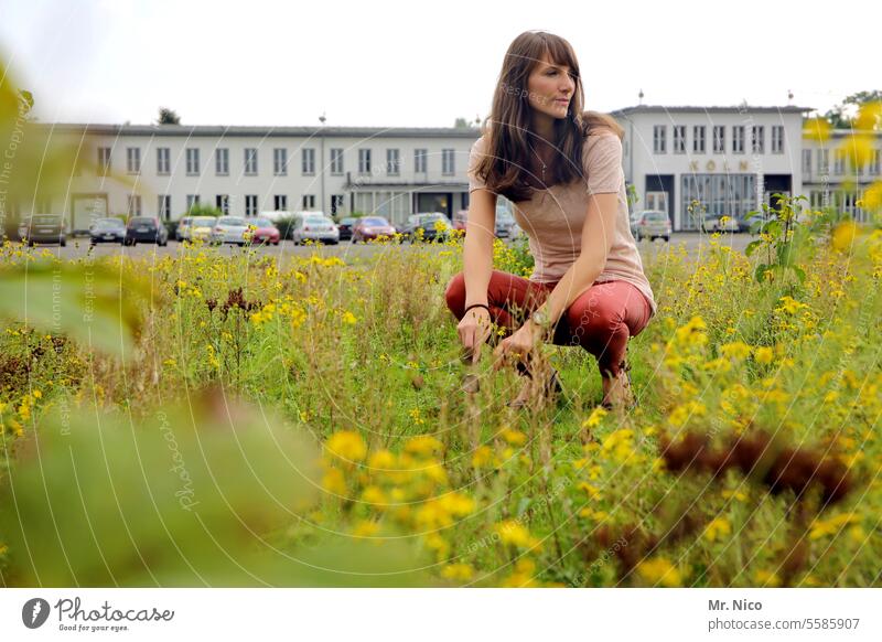 woman natürlich hocken langhaarig Wiese Park Gras Natur attraktiv authentisch Umwelt Stadtbegrünung Stadtpark Gebäude Parkplatz beobachten Blick zur Seite
