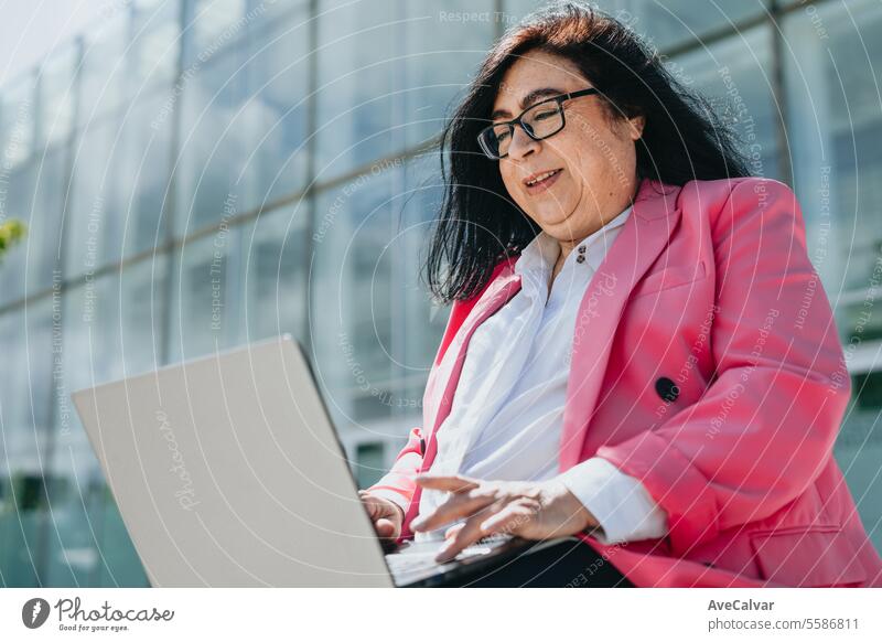 Lächelnde erwachsene Frau, die ein Online-Meeting auf einem Laptop auf einer Bank außerhalb der Arbeit sitzt. Frauen Person Computer Erwachsener