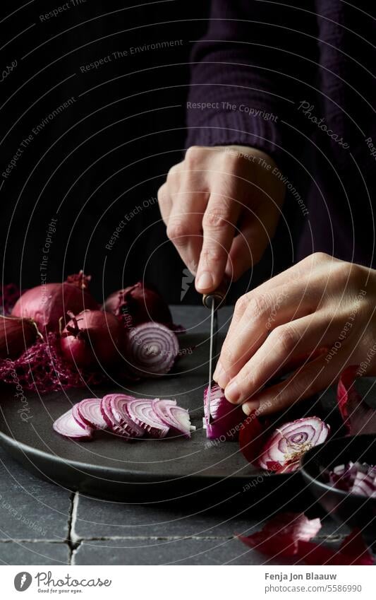 Schneiden frischer roter Zwiebeln in der Küche in einer stimmungsvollen Umgebung aufgenommen Essen zubereiten geschnitten Zwiebeln schneiden dunkel und launisch