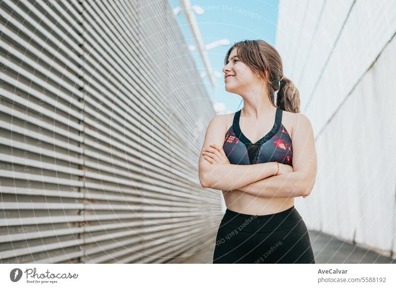 Porträt einer sportlichen, athletischen und trainierten lächelnden Frau mit verschränkten Armen in einer Straßenumgebung Sport Fitness Lifestyle Person jung