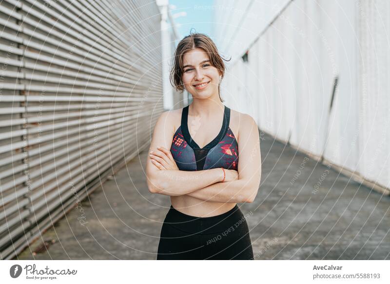 Fröhliche joviale gesunde junge Frau posiert zwischen Gebäude in städtischer Umgebung mit sportlicher Atmosphäre Frauen Lifestyle Sport Fitness Übung Person