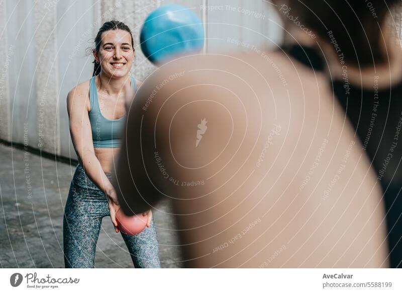 Zwei fitte Frauen treiben zusammen Sport und benutzen einen Medizinball, um ihren Körper zu straffen. Urbane Szene. passen Fitness Training Übung Fitnessstudio