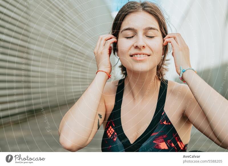 Porträt eines jungen Mädchens in Sportkleidung, das in einer städtischen Umgebung in die Kamera lächelt und ihr Haar berührt. Frau Frauen Musik Person Schönheit