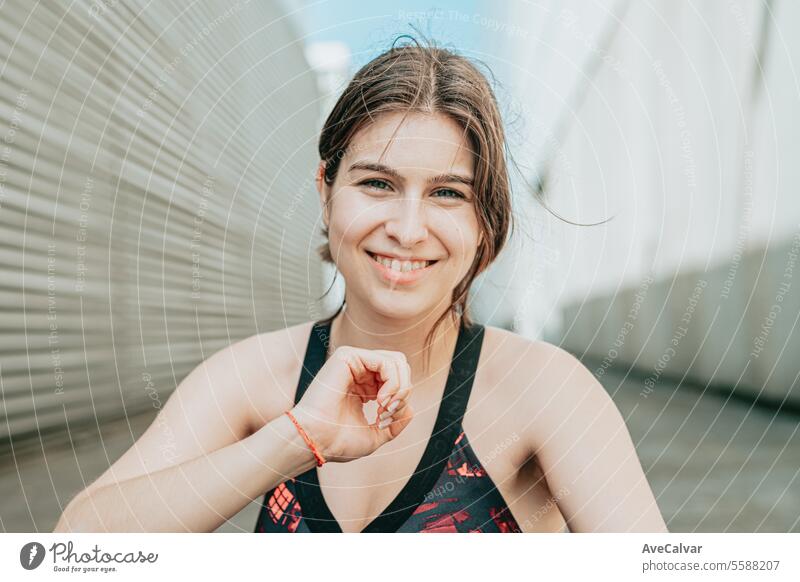Porträt eines jungen Mädchens in Sportkleidung, das in einer städtischen Umgebung in die Kamera lächelt und ihr Haar berührt. Frau Person Frauen Glück Kaukasier
