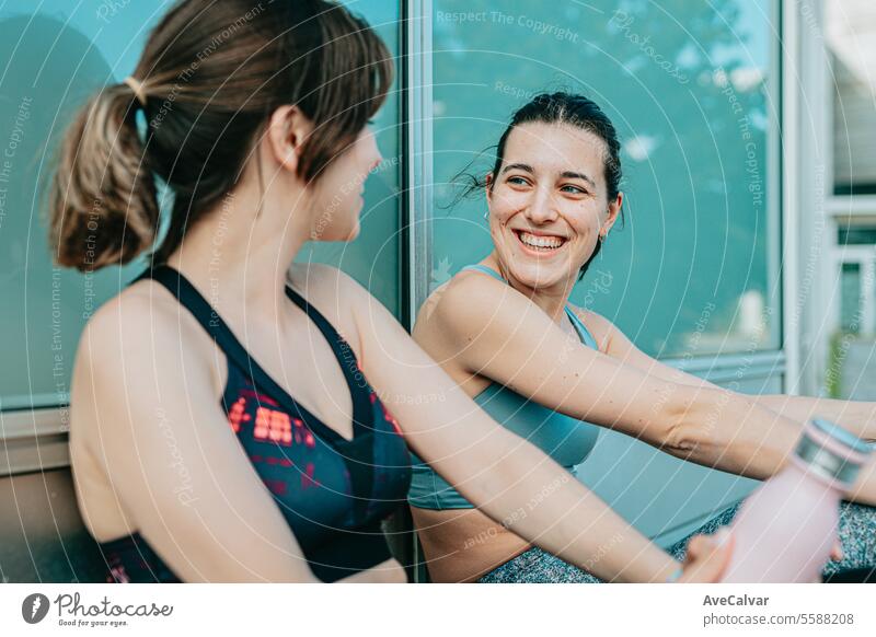 Zwei junge, fitte, fröhliche Mädchen sitzen ausgeruht nach dem Sport und freuen sich, ihre sportlichen Ziele zu erreichen. Pool Frauen Wasser Lifestyle