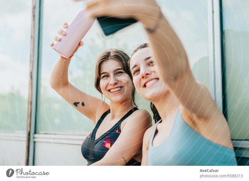 Zwei Influencer machen mit ihren Handys, Videos und Selfies Werbung für Sportprodukte. Lifestyle jung Person im Freien urban Freunde Training Gesundheit Frau