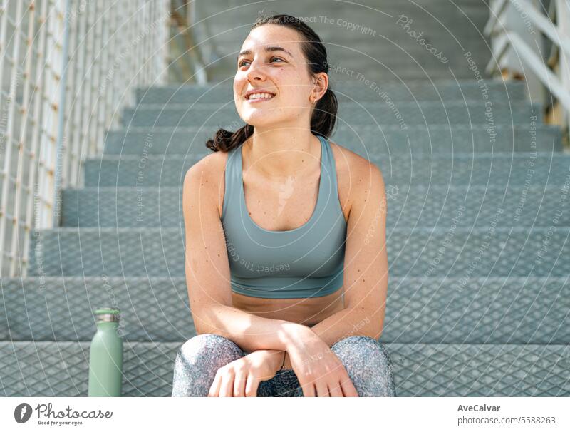 Porträt eines lächelnden und fröhlichen jungen Mädchens in Sportkleidung, das auf einer Treppe sitzt. Sport in der Stadt. sportlich Lifestyle Fitness passen