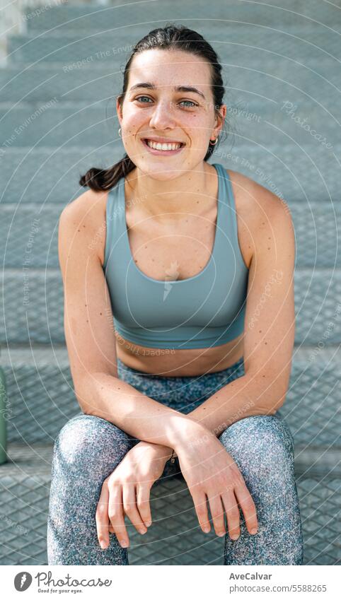 Porträt eines lächelnden weiblichen Fitnesstrainers, der in einer städtischen Straßenumgebung in die Kamera schaut. Person Sport sportlich Frauen Lifestyle
