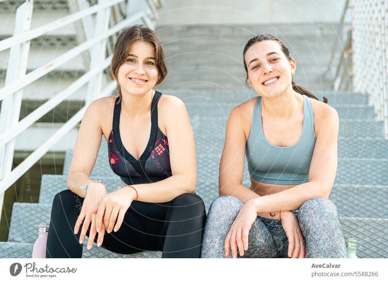 Porträt von zwei lächelnden weiblichen Personal Fit Trainern, die in einer städtischen Straßenumgebung in die Kamera schauen. Lifestyle Fitness Sport Frau Übung