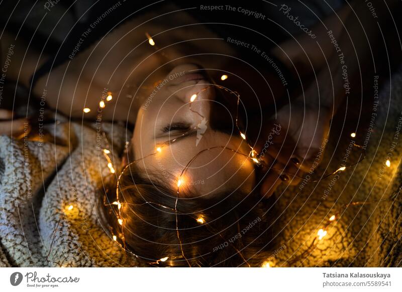 Eine Frau mit Schulterklappen-BH inmitten der leuchtenden Weihnachtsbeleuchtung Wandleuchter Lügen glühend Licht Schnur Lichter beleuchtet verwickelt Nacht