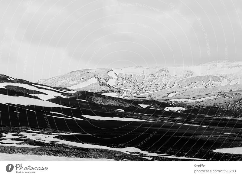 Schneeschmelze auf Island Hügel Berge schneebedeckt Islandwetter Schneeflecken Felsen Bergseite schwarz weiß grau Islandreise felsig isländische Landschaft