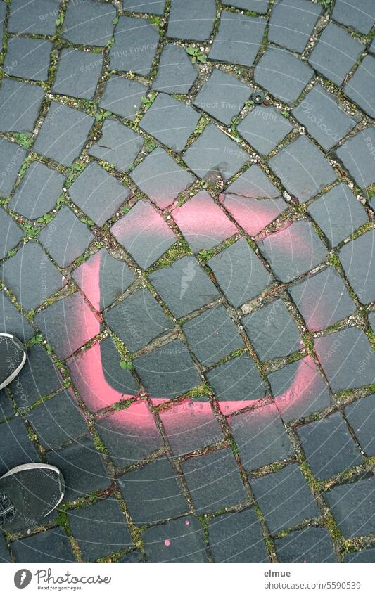 Rand einer mit rosa / pink markierten, quadratischen Stelle auf Straßenpflaster und Schuhspitzen Markierung Schablone sprayen markierte Stelle Pflasterstraße