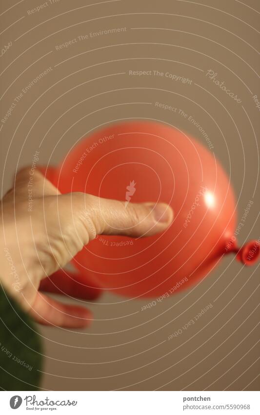festhalten und loslassen. eine hand an einem roten luftballon trennung beziehung Gefühle Liebe Partnerschaft symbolbild schweben angst sicherheit loslösung