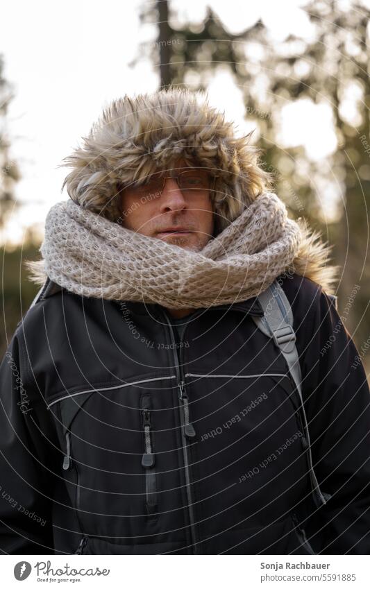 Ein Mann mit einer Fellkaputze und einem Schal Kaputze Winter Kälte Lifestyle Außenaufnahme Porträt sehen Brille Mensch hübsch 50-60 Jacke schwarz Gesicht Tag