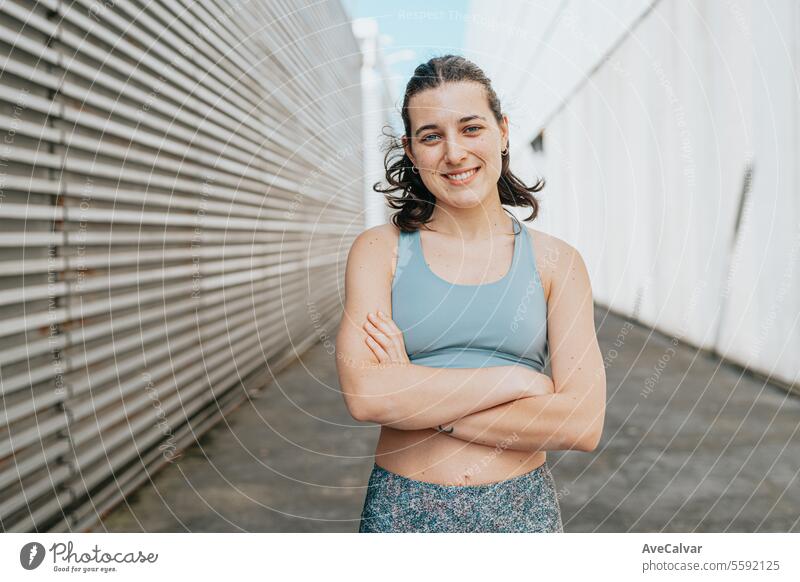 Porträt einer sportlichen, athletischen und trainierten lächelnden Frau mit verschränkten Armen in einer Straßenumgebung Schönheit Model Frauen Person jung