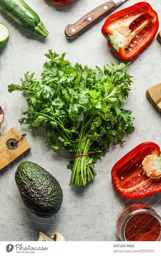 Bündel frischer Petersilie auf grauem Tisch mit anderen gesunden Gemüsezutaten, Ansicht von oben Haufen Gesundheit Zutaten Top Geschmack Gewürz Vegetarier