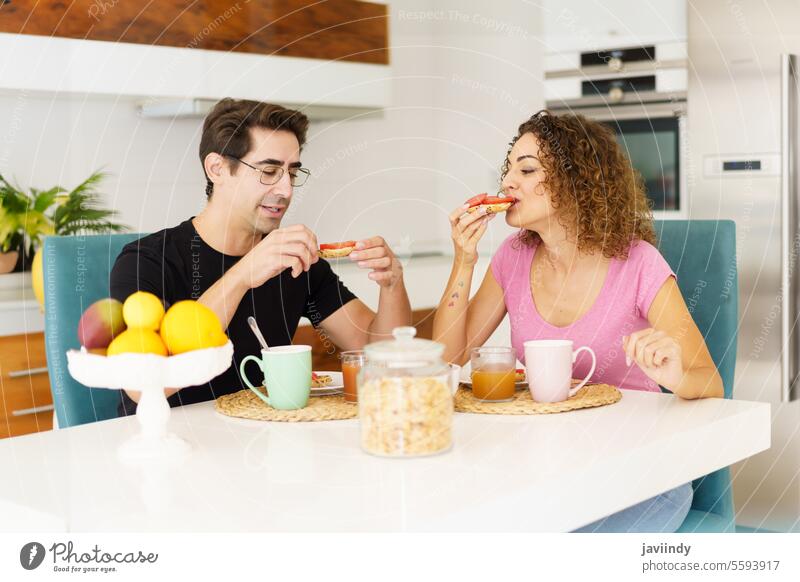Glückliches erwachsenes Paar sitzt am Esstisch und spricht beim Frühstück essen Salatbeilage gesunde Ernährung Lächeln sprechen Kommunizieren Gespräch männlich