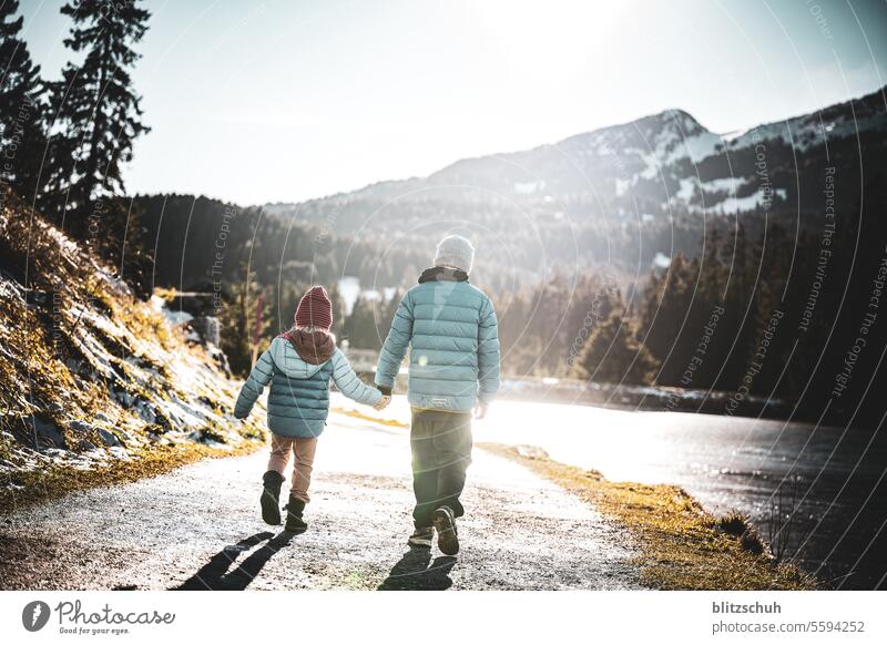 Zwei Kinder laufen zusammen an einem schönen November Nachmittag am Ufer eines Bergsees entlang Bruder Schwester Geschwister Laufen Wandern See Mädchen Junge