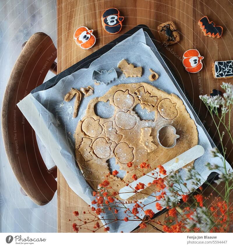 Ausstechen von Keksteig auf dem Küchentisch zum Backen von Halloween-Keksen Cookies backen orange austricksen oder behandeln Teigwaren Fledertiere Kürbis