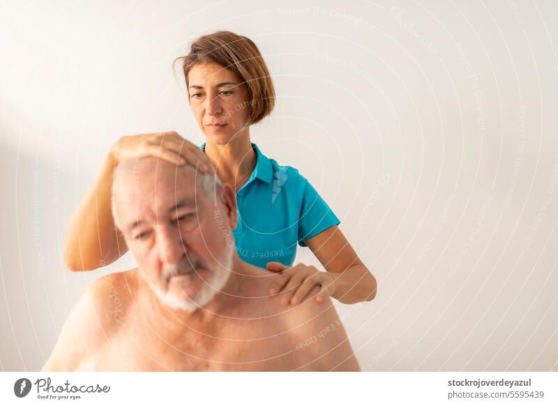 Eine Physiotherapeutin führt Dehnübungen am Nacken ihres Patienten, eines älteren Mannes, durch, um seine Rehabilitation und sein Wohlbefinden zu fördern Frau