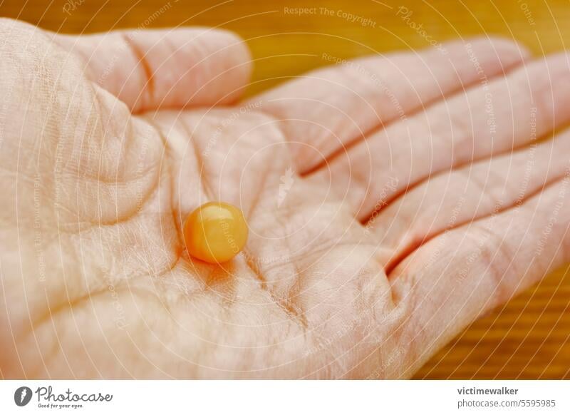 Orangefarbene Pille in weiblicher Hand Medizin Gesundheitswesen Tablette orange Studioaufnahme medizinisch Apotheke Medizinischer Beruf Textfreiraum