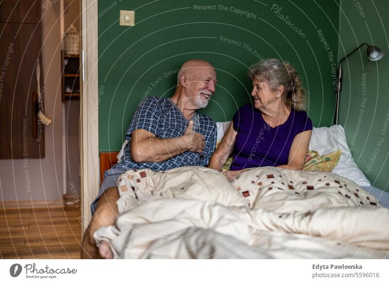Älteres Paar sitzt im Bett und schaut sich liebevoll an Schlafzimmer Morgen Liebe Bonden Geliebter Glück sprechend Lächeln Freude genießend Zuneigung Romantik