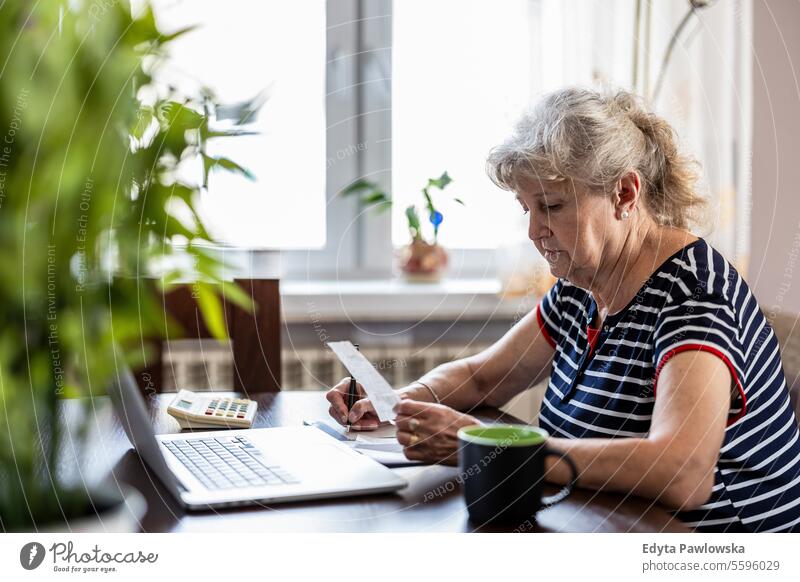 Ältere Frau, die ihre Finanzen zu Hause überprüft echte Menschen Senior reif Kaukasier älter heimwärts alt Alterung häusliches Leben Großmutter Rentnerin