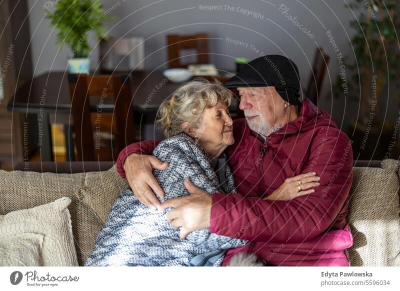 Älteres Ehepaar trägt wegen der hohen Strompreise Winterkleidung im Haus kalte Temperatur Winterbekleidung warme Kleidung unbequem Traurigkeit gefroren