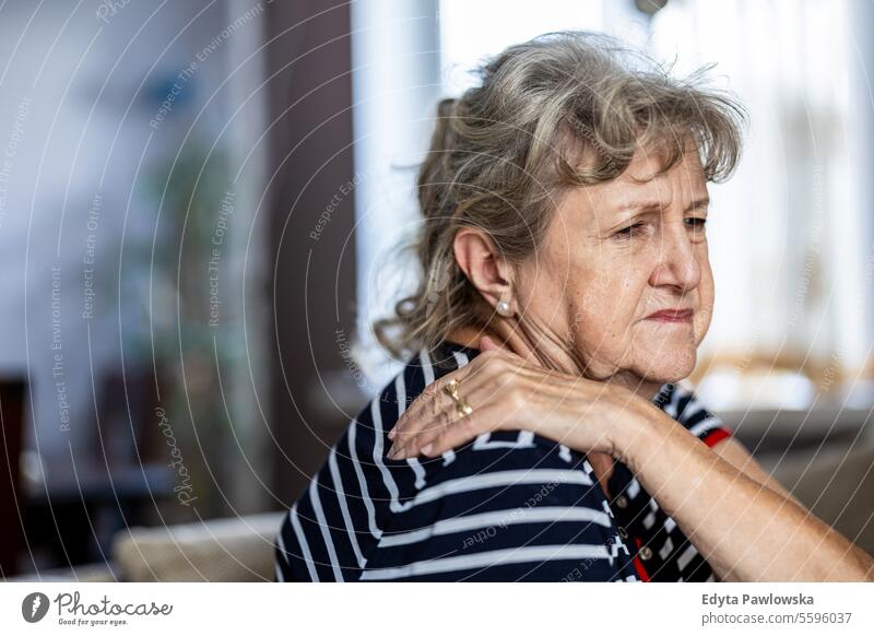 Porträt einer älteren Frau, die unter Nackenschmerzen leidet, während sie zu Hause auf dem Sofa sitzt echte Menschen Senior reif Kaukasier heimwärts alt