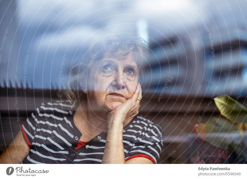 Porträt einer älteren Frau, die durch ein Fenster schaut echte Menschen Senior reif Kaukasier heimwärts Haus alt Alterung häusliches Leben Großmutter Rentnerin