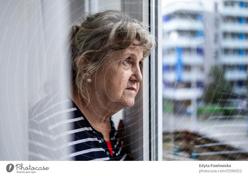 Porträt einer älteren Frau, die durch ein Fenster schaut echte Menschen Senior reif Kaukasier heimwärts Haus alt Alterung häusliches Leben Großmutter Rentnerin