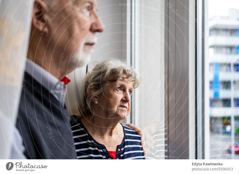 Porträt eines älteren Paares, das zu Hause aus dem Fenster schaut echte Menschen Frau Senior reif männlich Mann Zusammensein Kaukasier heimwärts alt Alterung