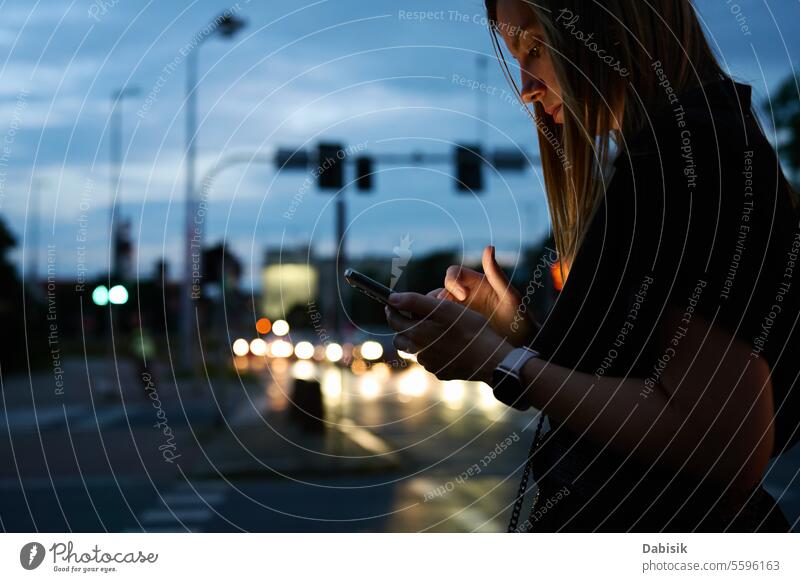 Frau benutzt Smartphone auf abendlicher Straße Nacht Großstadt Mitteilung online benutzend im Freien Browsen Hand Beteiligung Gerät Business soziale Netzwerke