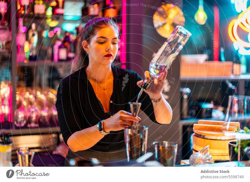Fokussiert Schöne Bardame mit blonden Haaren steht an der Theke und bereitet einen Cocktail in einem Nachtclub vor Frau Barkeeper Alkohol Jigger Flasche