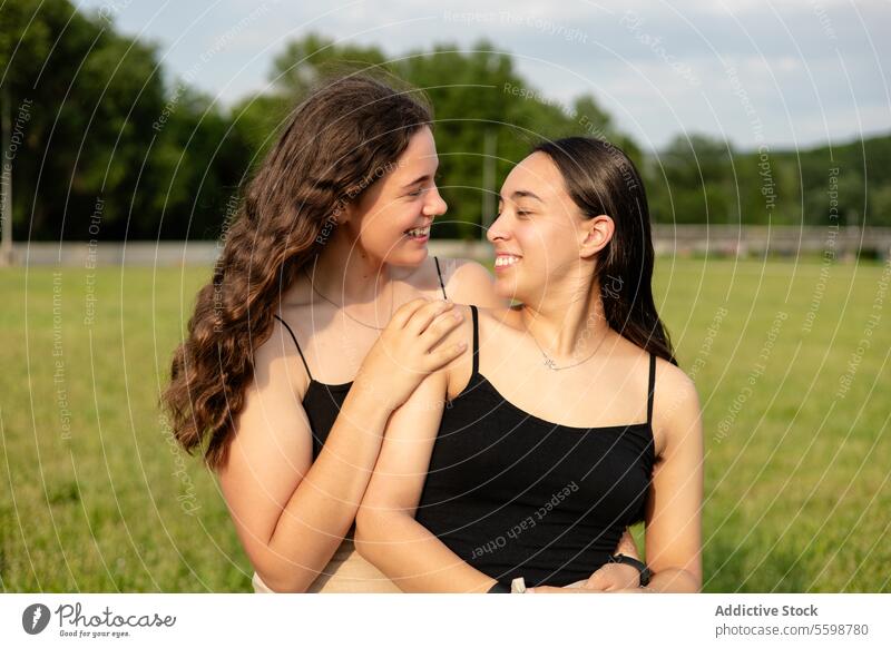Zwei glückliche junge Frauen schauen sich in der Natur an Umarmen Lächeln Feld Liebe Gesellschaft Angebot Starrer Blick Zuneigung Sommer im Freien Anschluss