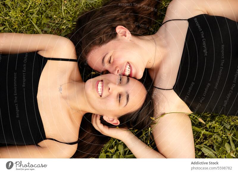 Glückliche Frauen, die in einem Moment der Zuneigung im Gras liegen lachen lgbt Stolz lesbisch Paar Anschluss Liebe im Freien Fröhlichkeit Intimität binden
