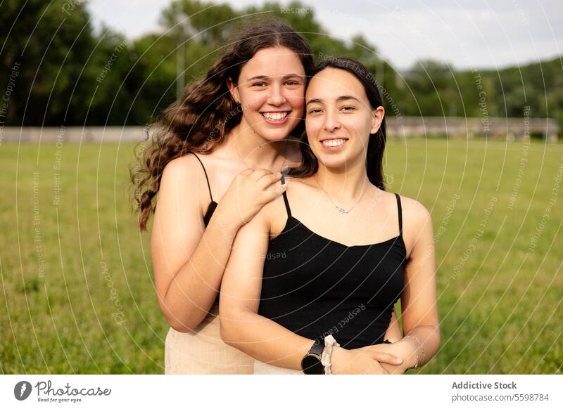 Glückliche junge Frauen schauen in der Natur in die Kamera Lächeln Umarmen lässig Feld Liebe lgbt Stolz lesbisch Paar grün im Freien Fröhlichkeit Freude