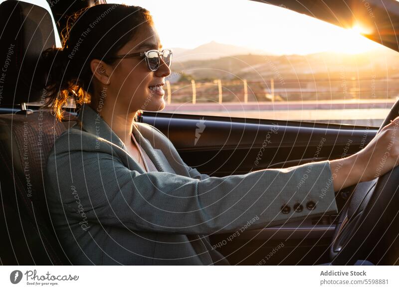Glückliche Geschäftsfrau mit Sonnenbrille am Steuer eines Autos Frau Exekutive PKW fahren Porträt Lächeln schön jung Fahrer Sitz Armaturenbrett Lenkrad