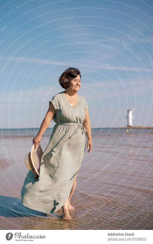 Frau mit Blick auf den Meereshorizont Strand Kleid Sonne Hut Sand MEER Horizont Himmel Starrer Blick Sommer Küste Wasser winken Schutzschild Hand stehen