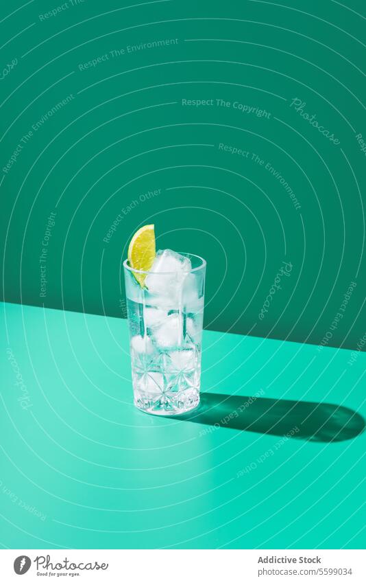 Erfrischende Limette Gin Tonic Glas auf Teal Hintergrund Zitrone Kalk Wasser Eis blaugrün Schatten erfrischend Getränk cool trinken Scheibe Zitrusfrüchte