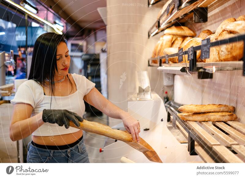 Junge Verkäuferin packt Brot in eine Tüte Porträt lateinamerikanisch Frau Verkauf Assistent Kunde Laden Business Unternehmer Lebensmittel Café Dienst Bäckerei