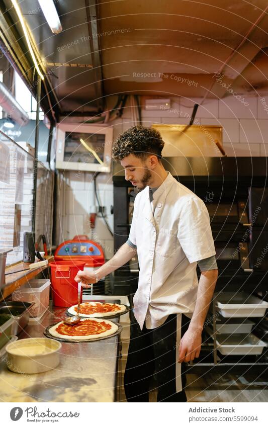Pizzamann beim Pizzabacken in der Küche einer Pizzeria arabisch Mann Lebensmittel Restaurant Tomate Saucen vorbereitend Italienisch Essen zubereiten Bäcker