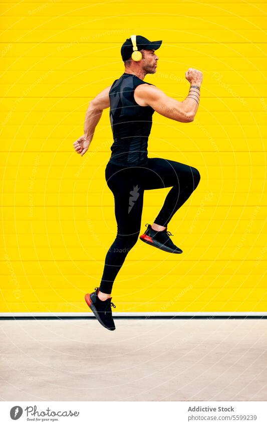 Mittlerer erwachsener Mann beim Springen und Trainieren in der Stadt Sportler springen Kopfhörer Straße Lifestyle Ganzkörper Seitenansicht Verschlussdeckel