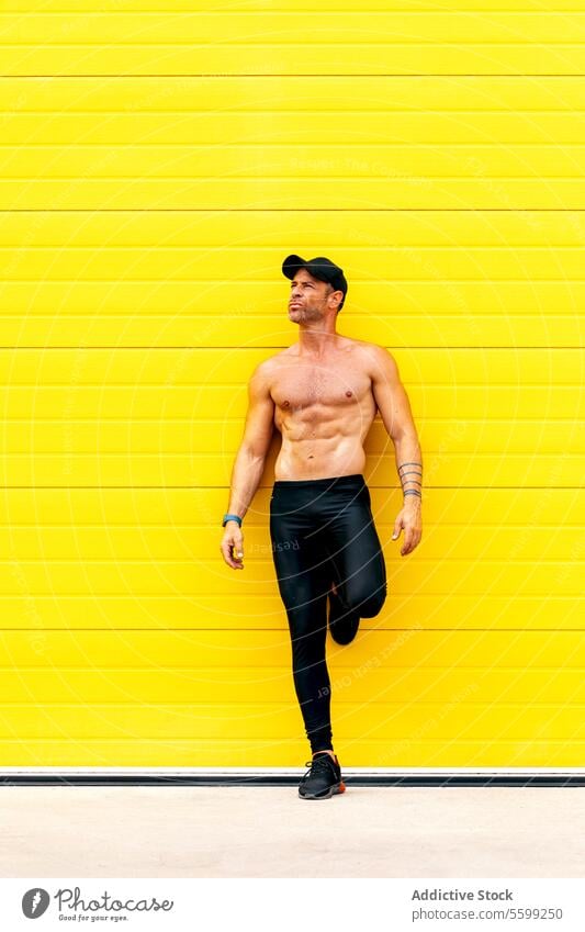 Mann ohne Hemd denkt nach, während er sich an die Wand lehnt Sportler nachdenklich Verschlussdeckel Wegsehen Stehen Straße gelb Denken nackter Torso muskulös